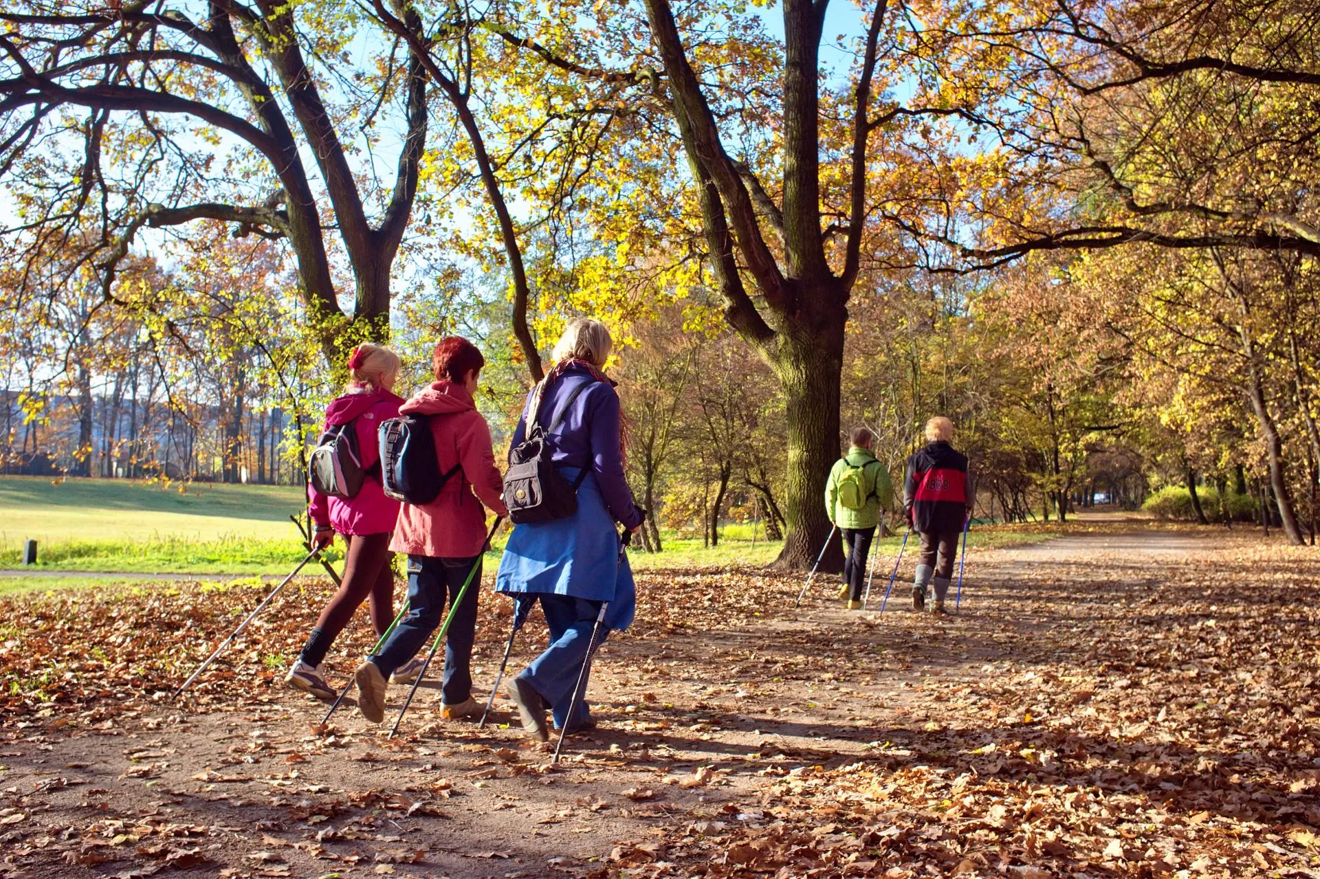 Group walking beside a calm river with railings